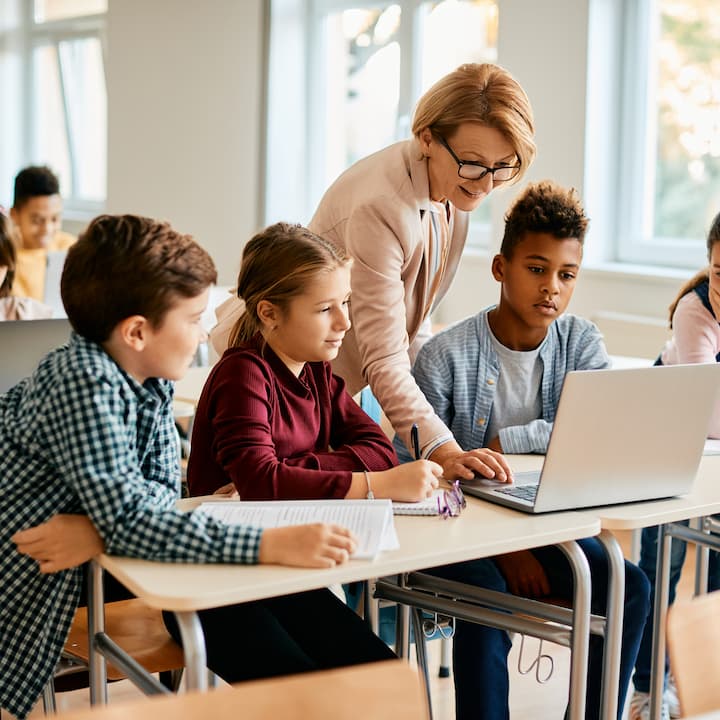 A teacher showing her students something on a laptop | Services provided for Educational Professionals